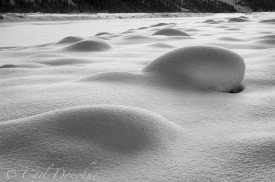 Snow covered boulders glisten in late evening sun. Winter light on fresh snow, along the frozen Kennicott River, or Kennecott River, Wrangell - St. Elias National Park and Preserve, Alaska.