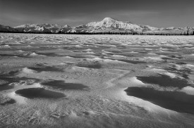 Black and white photo of Mount Sanford, one of the highest peaks in the Wrangell Mountains, at dawn, from a small frozen kettle pond. Winter snow creates patterns on the frozen lake. Mt. Sanford, Wrangell - St. Elias National Park and Preserve, Alaska.